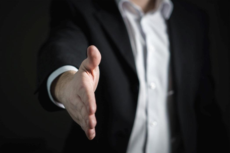 A man in a suit extending his hand