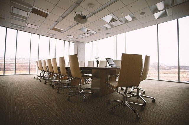 A conference room with beige chairs and a wooden floor.