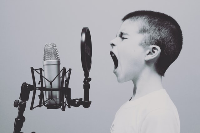 a boy screaming at a microphone 